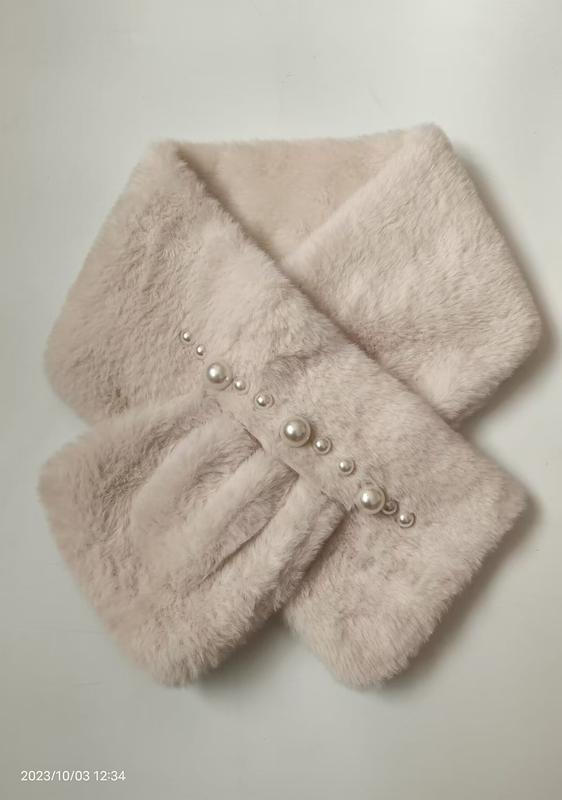 Soft cream faux fur crossover neck scarf with pearl bead embellishments arranged diagonally, folded flat on white background