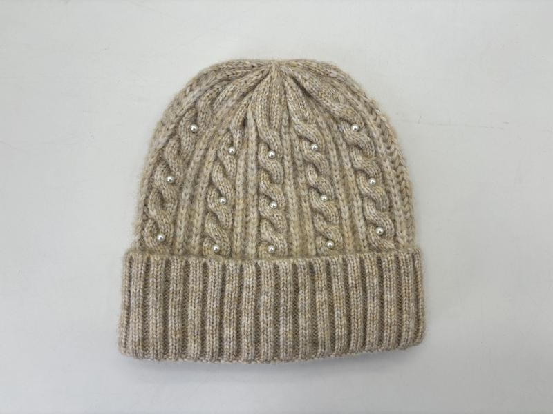 Beige cable knit winter beanie hat with pearl bead embellishments and ribbed cuff, flat lay on white background