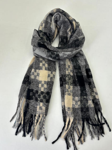 Folded woven scarf in black, grey and cream patchwork check pattern with tassel fringe ends on white background
