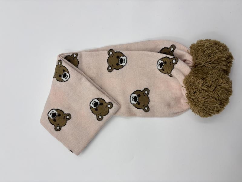 Pink knitted scarf with all-over teddy bear face pattern and large olive green pom-pom end detail