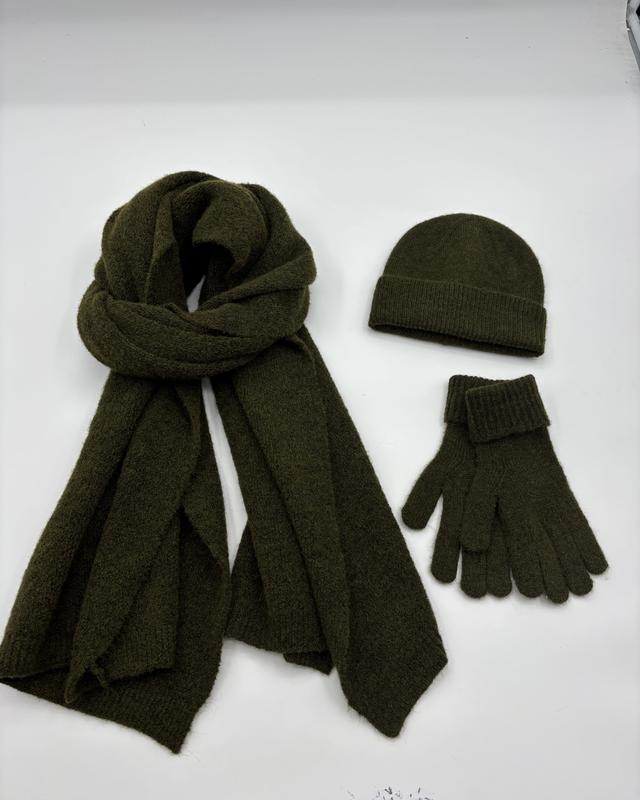 Olive green knit winter accessories set with oversized scarf, ribbed beanie hat and matching gloves on white background
