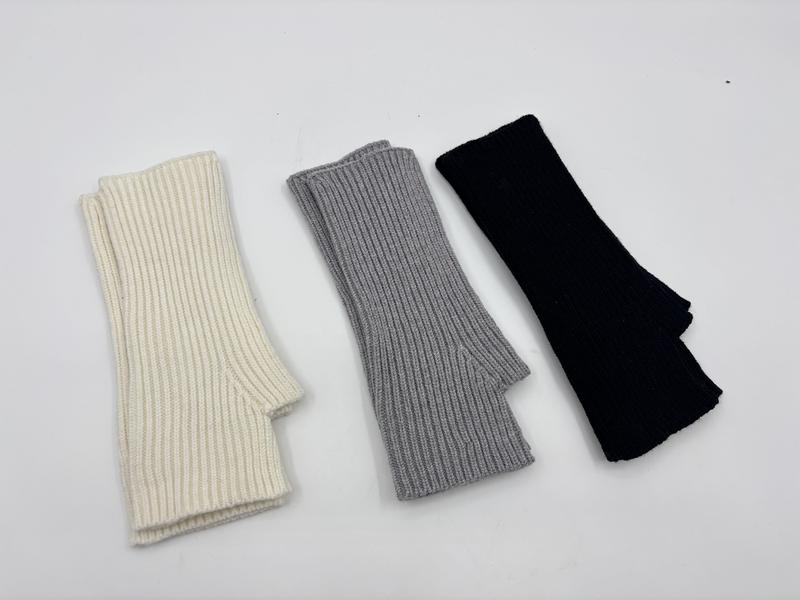 Three ribbed knit fingerless gloves arm warmers laid flat in ivory, grey, and black on white background