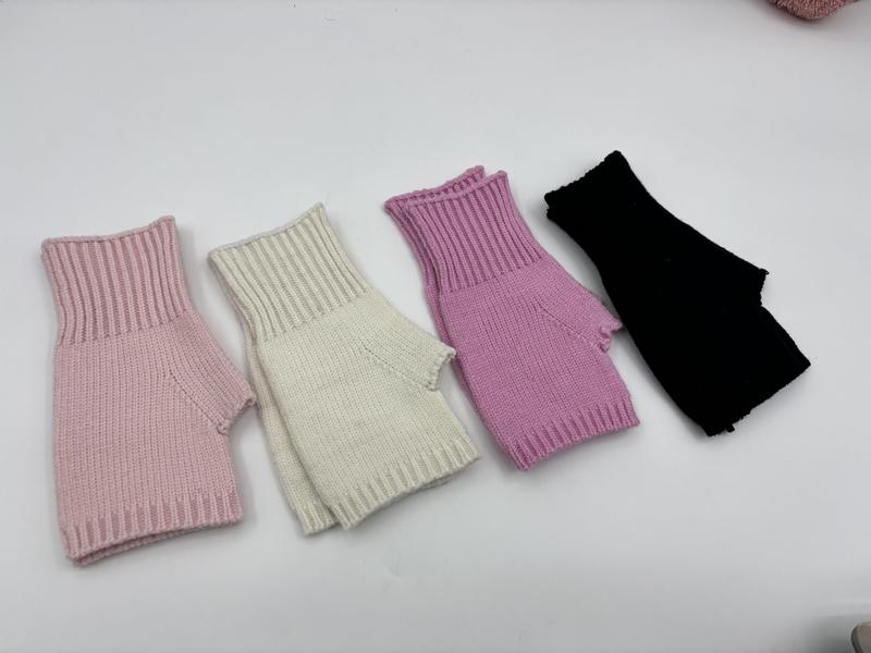 Four ribbed knit fingerless gloves in pink, cream, lilac, and black laid flat on white surface