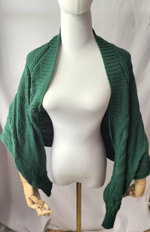 Green cable knit open front cocoon shrug cardigan with balloon sleeves displayed on a dress form mannequin