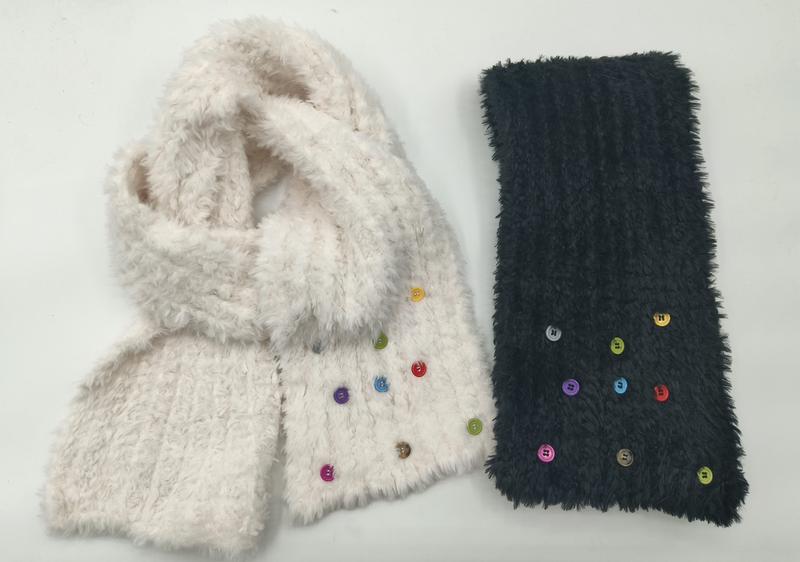 Two fuzzy knit scarves with multicolor buttons, one cream white and one navy blue, displayed flat on white background