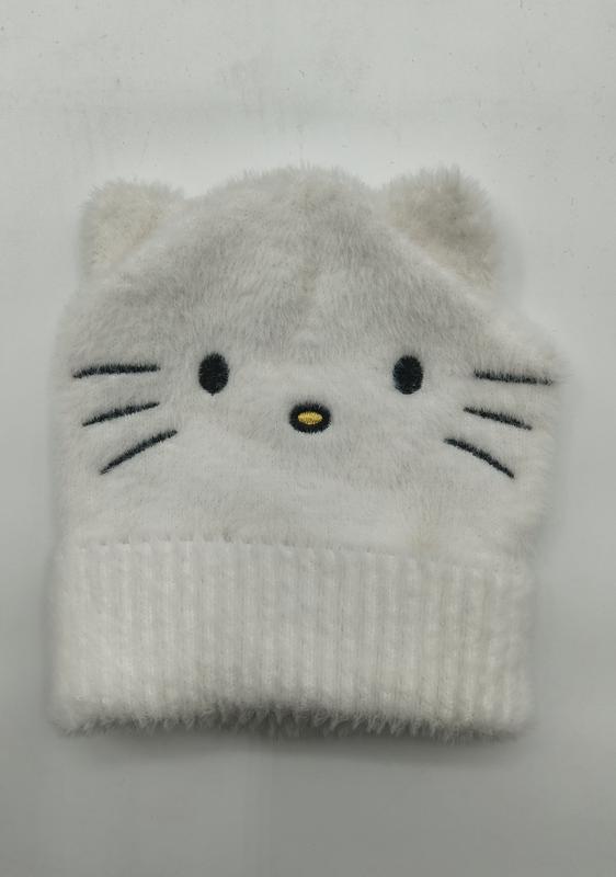 White fluffy knit beanie hat with embroidered cat face, whiskers, and small ears, folded flat on white background