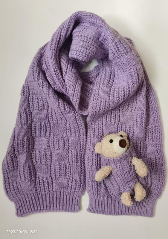 Lavender purple chunky knit oversized cardigan with wide shawl collar and small teddy bear stuffed in front pocket, flat lay view