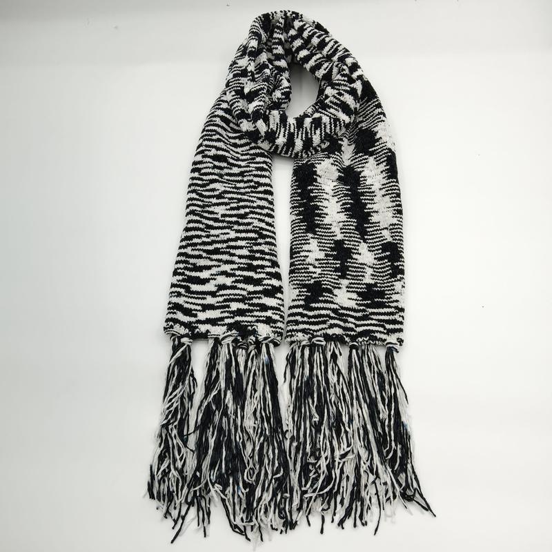 Black and white chunky knit scarf with zebra stripe pattern, bold graphic design, and long tassel fringe ends laid flat