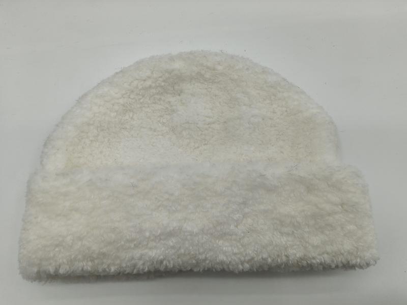 White cream sherpa fleece beanie hat with curly teddy texture, laid flat on white background, cozy winter accessory