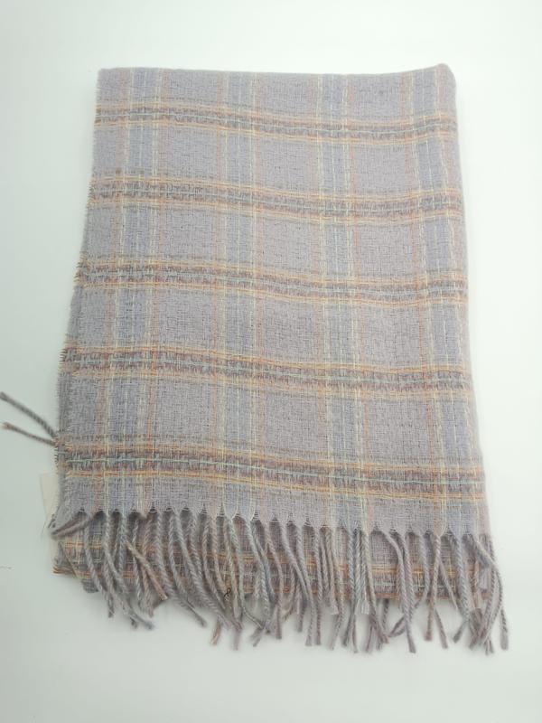 Folded light grey plaid woven throw blanket with peach and gold check pattern and twisted fringe trim