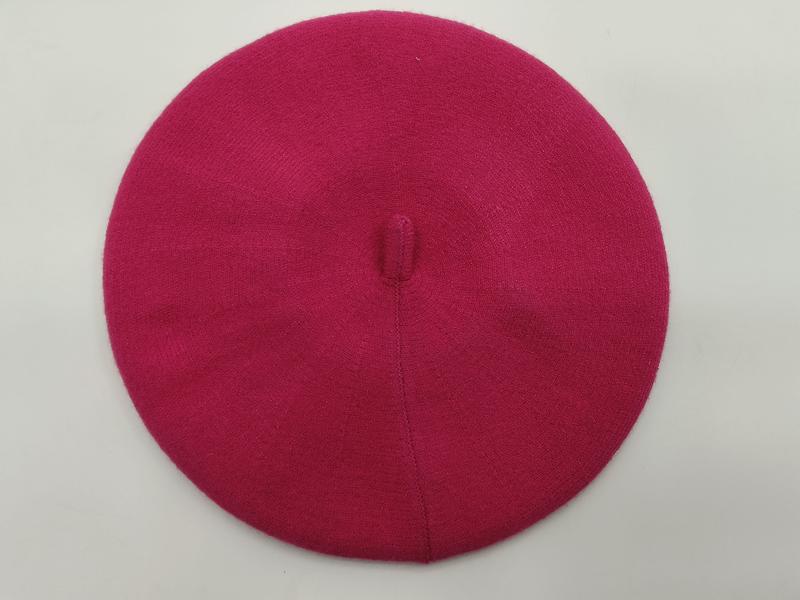 Flat lay of a hot pink fine knit wool beret with center button top on white background