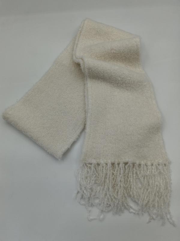 Soft cream boucle knit scarf folded on white background, showing textured fabric and knotted fringe ends