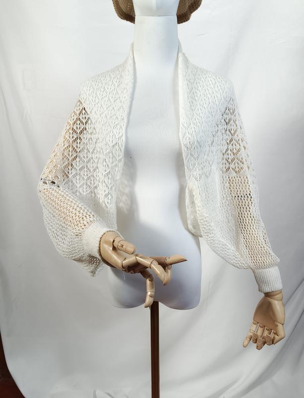 White open-weave lace knit cropped bolero shrug with long balloon sleeves and ribbed cuffs on a mannequin