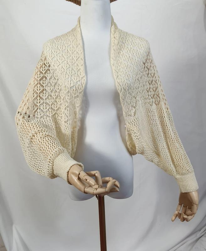 Cream ivory open-knit crochet bolero shrug with balloon bishop sleeves and ribbed cuffs on a mannequin