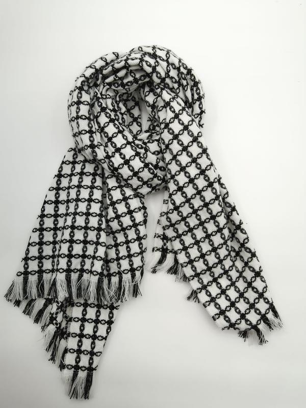 Black and white chain-link pattern woven scarf with fringe tassel ends, loosely draped on white background