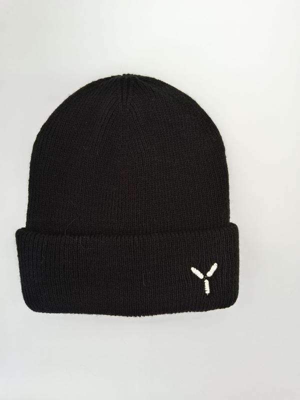 Black ribbed knit beanie hat with folded cuff and small white embroidered Y logo on light gray background