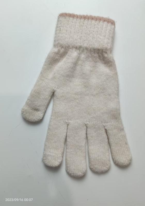 Single cream-colored soft knit winter glove with ribbed cuff and subtle pink stripe accent, laid flat on white surface