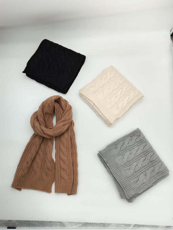 Four cable knit scarves in black, cream, camel, and gray displayed on white surface, one unfolded showing full length