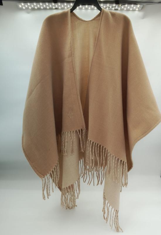 Camel beige fringed wrap poncho cape in soft wool blend, open front design with tassel hem, displayed on hanger