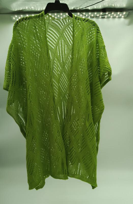 Lime green crochet lace kimono cardigan with diamond chevron pattern hanging on black hanger against white wall