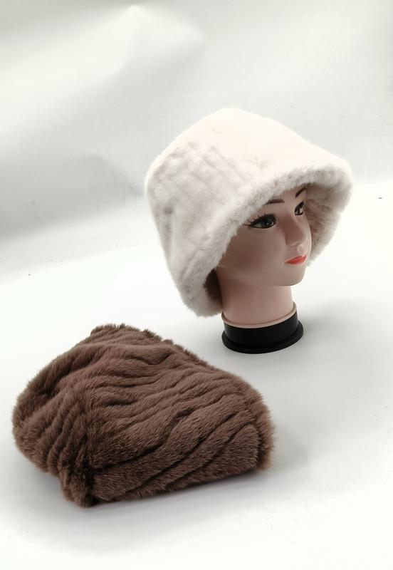 White faux fur bucket hat on mannequin head with brown ribbed plush beanie hat laid flat on white surface