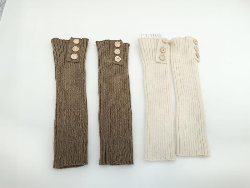 Two pairs of ribbed knit leg warmers with wooden buttons at top, one taupe and one cream, laid flat on white background