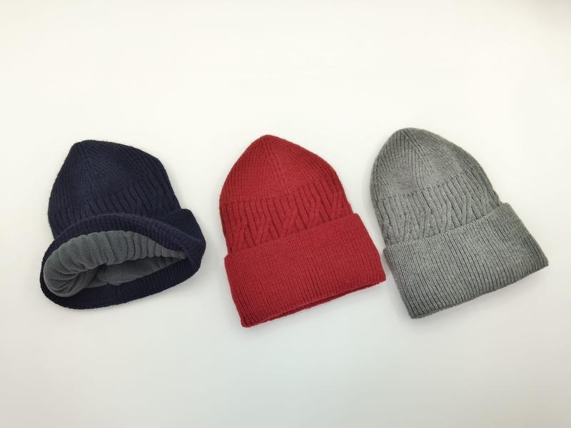Three ribbed knit beanies in navy blue, red, and grey displayed on white background, navy hat showing grey fleece lining
