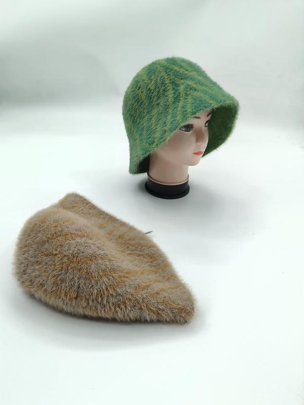 Green striped fuzzy knit bucket hat on mannequin head with matching tan beige flat folded hat on white surface