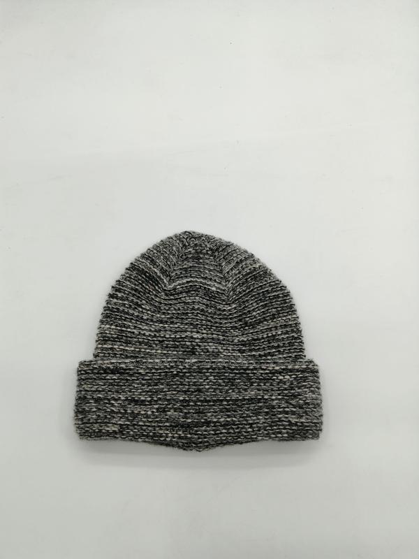 Flat lay of a grey marled chunky ribbed knit beanie hat with folded cuff on white background