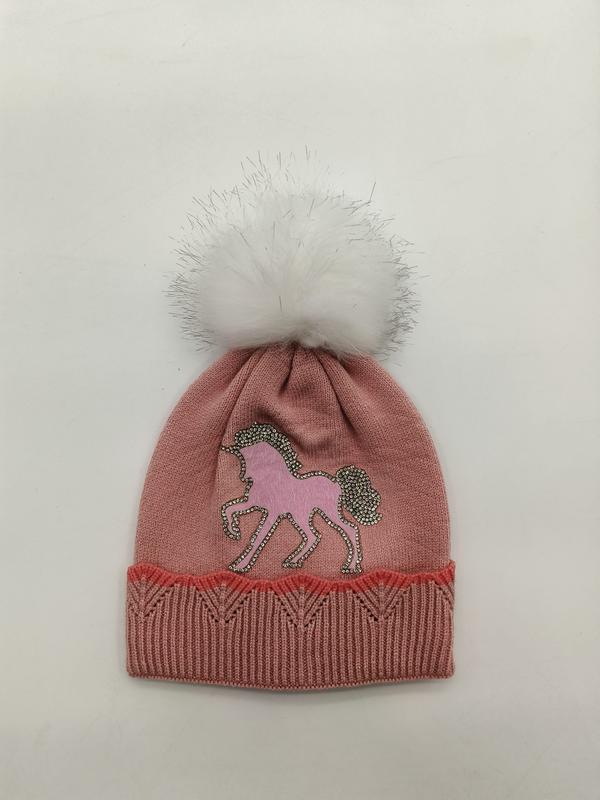 Pink knitted girls winter beanie hat featuring rhinestone unicorn applique and fluffy white faux fur pom pom on top