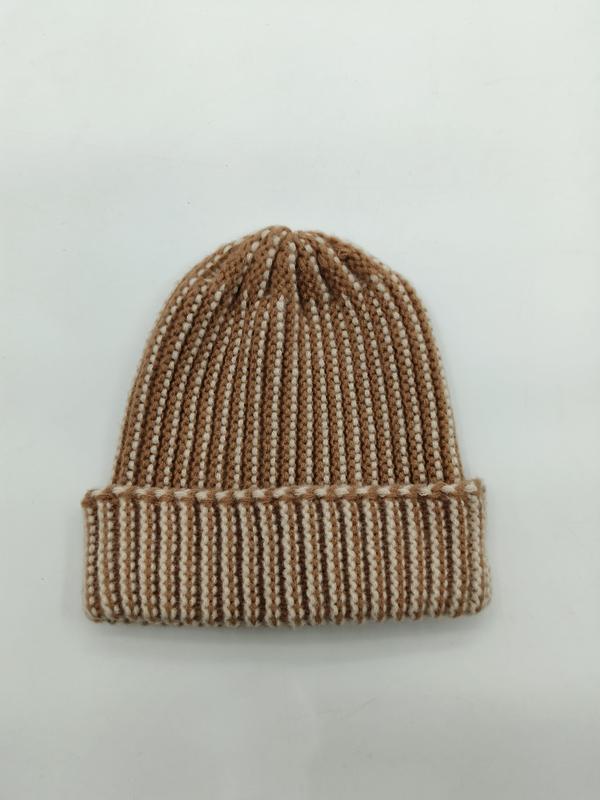 Flat lay of a camel and cream two-tone ribbed knit beanie hat with a folded cuff on a white background