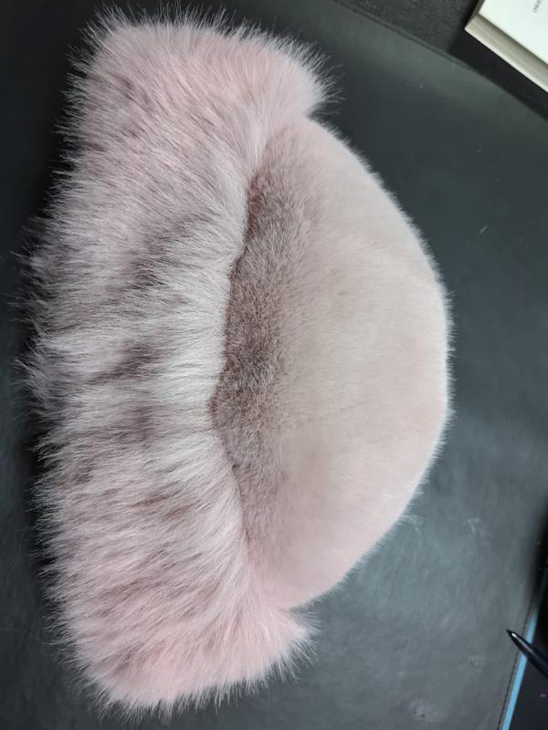 Soft blush pink faux fur half-moon shaped decorative pillow with taupe stripe detail on dark surface