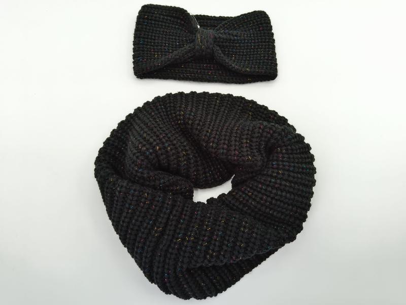 Black chunky knit infinity scarf coiled next to matching twist knot headband with multicolor metallic lurex threading