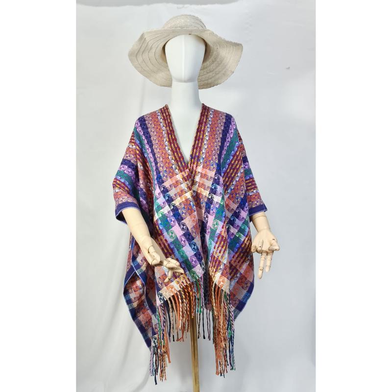 Mannequin wearing multicolor geometric woven poncho with fringe hem and wide-brim straw hat on white background
