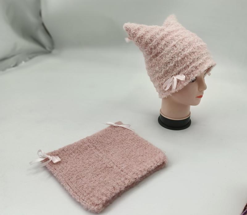 Pink fuzzy knit cat ear beanie hat with satin bows displayed on mannequin head beside matching knit neck warmer set