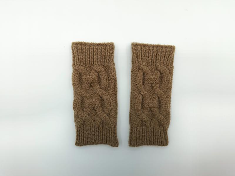 Pair of camel brown cable knit fingerless gloves laid flat on white background showing textured braid pattern