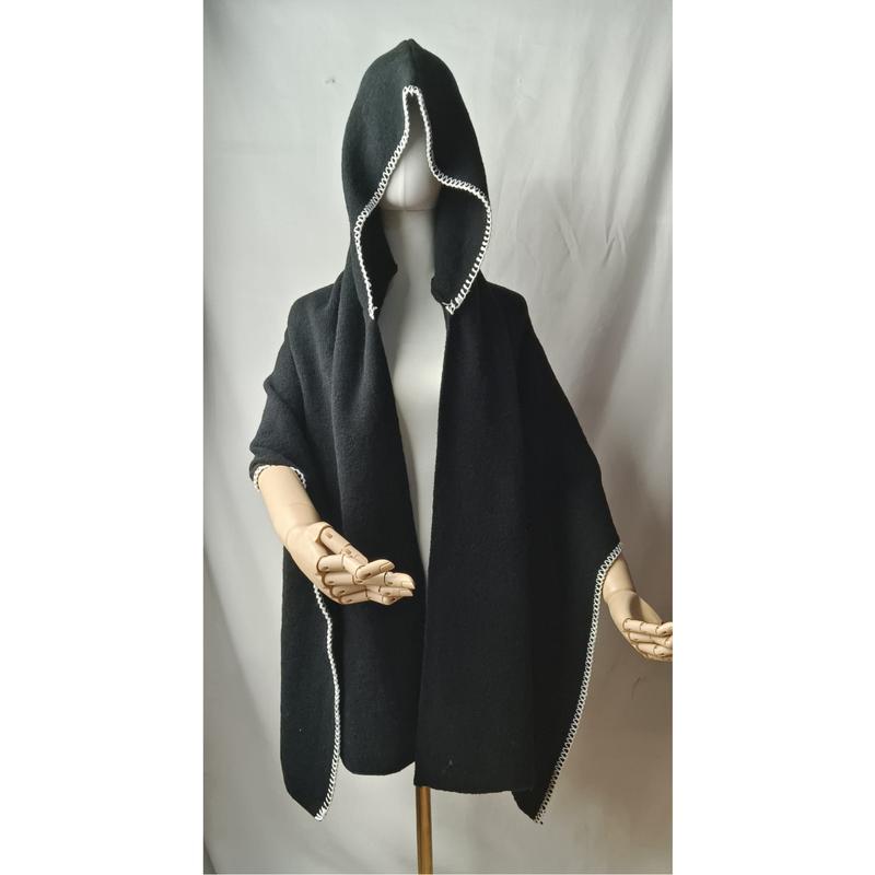 Black hooded poncho cape with white crochet border trim displayed on mannequin with wooden artist hands
