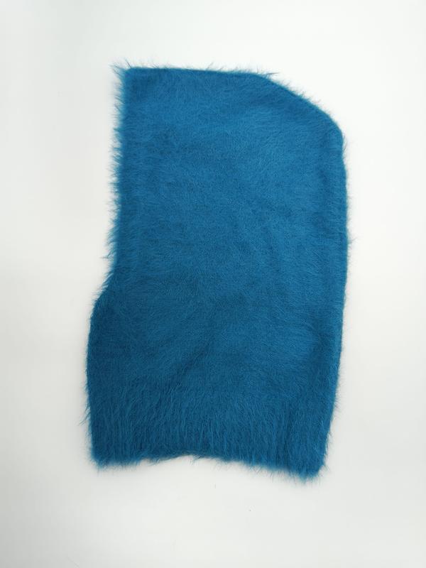 Teal blue fluffy angora-style knit balaclava hood laid flat on white background showing soft texture