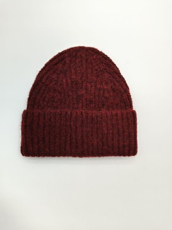 Dark burgundy chunky ribbed knit beanie hat with folded cuff, laid flat on white background