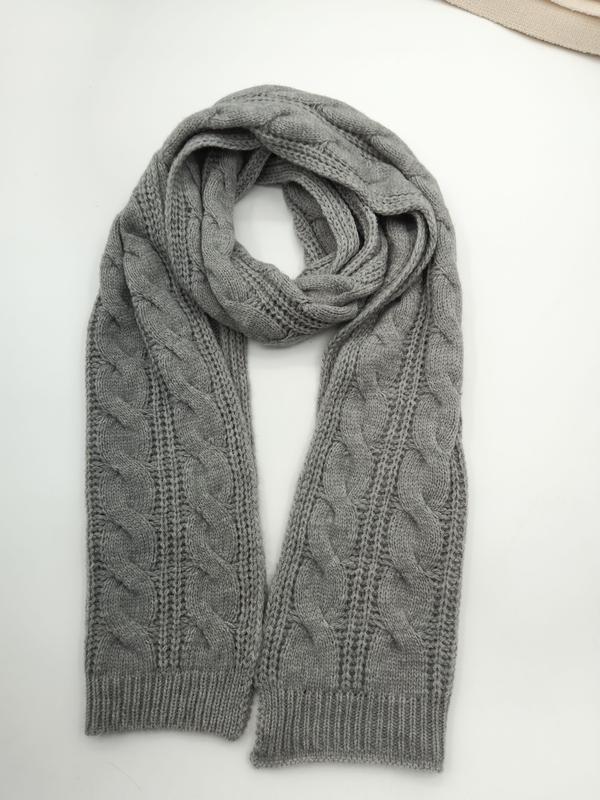 Gray cable knit scarf looped and laid flat on white surface showing braided texture and ribbed cuffs
